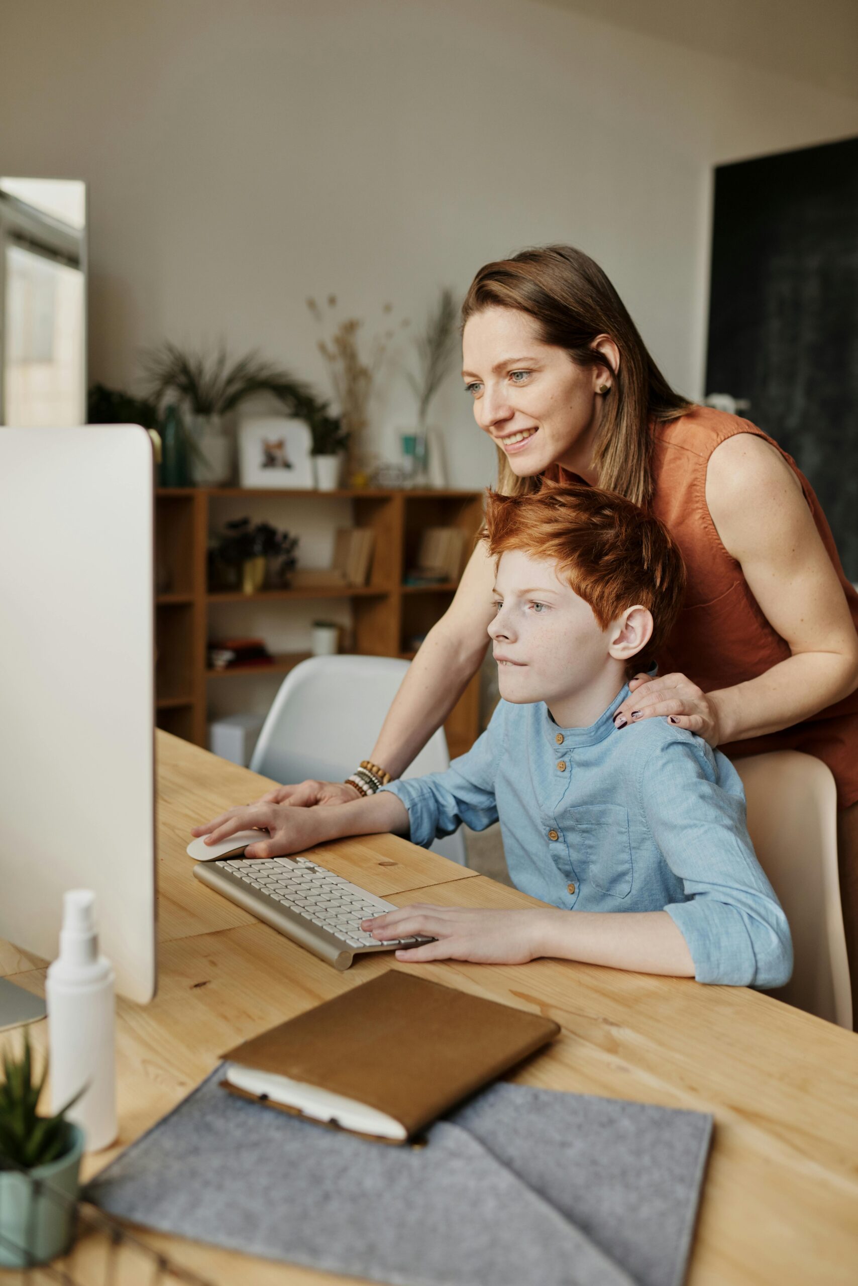 A mother helps her son with online learning on a home computer.